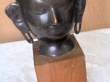 a small statue of a buddha head on a wooden block