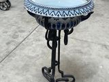 a blue and white bird bath on a black stand