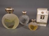 three perfume bottles and a box of perfume sitting on a table