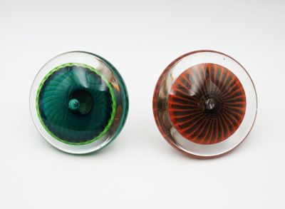une paire d'yeux en verre verts et rouges posés sur une surface blanche