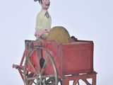 a toy of a man sitting in a wagon with a hat on