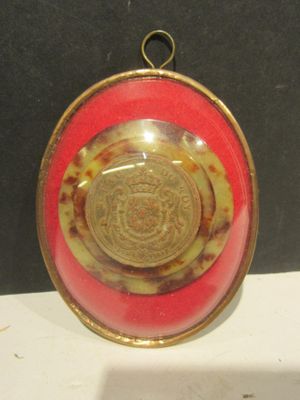 a picture of a red and gold plate with a gold medallion on it
