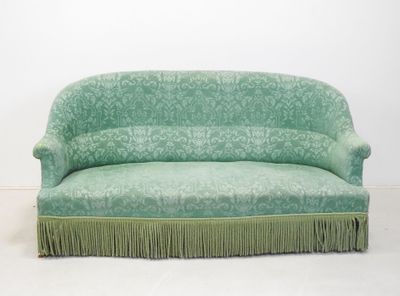 un canapé vert orné de franges dans une pièce