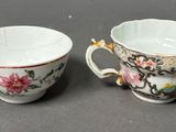 pair of porcelain cups with floral designs on them sitting on a table