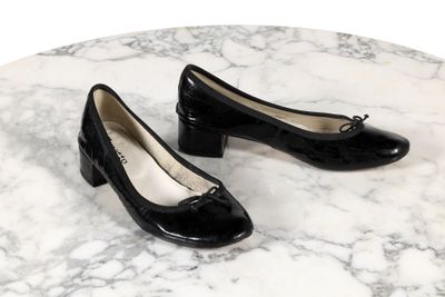 une paire de chaussures noires posée sur une table en marbre, sur fond blanc