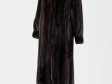 un manteau de fourrure noir posé sur un présentoir, sur fond blanc