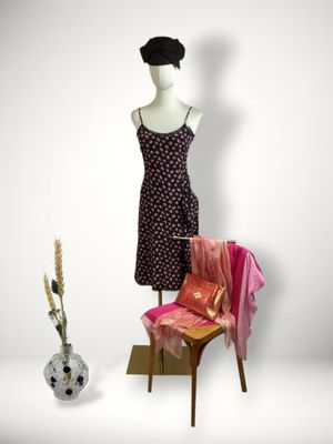 a mannequin sitting on a chair next to a dress on a mannequin stand