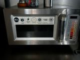 a silver microwave with a cup on top of it