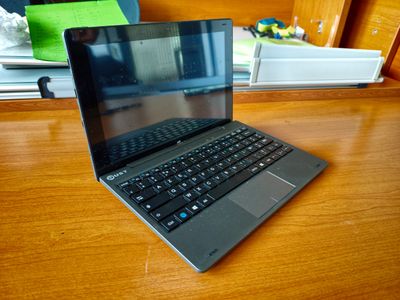 un ordinateur portable posé sur un bureau en bois devant une fenêtre