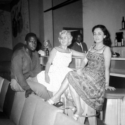black and white photograph of a group of people sitting at a bar