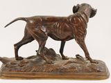 bronze statue of a dog standing on a rock on a white background