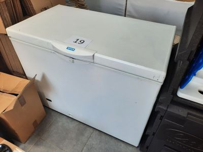 un congélateur coffre blanc posé à côté d'une pile de cartons