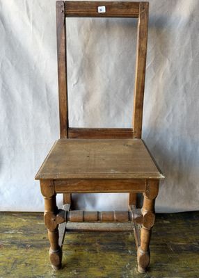 une vieille chaise en bois posée sur un parquet, près d'un mur blanc