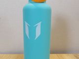 the water bottle is sitting on a wooden table with a white wall in the background