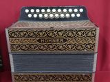 an old accordion sitting on top of a red table next to a remote control