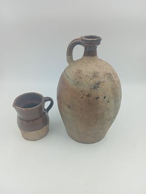 un vase marron et une tasse marron posés sur une surface blanche