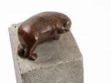 statue of a dog laying on a block of concrete on a white background