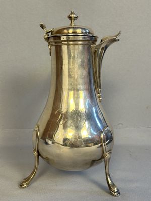 an antique silver coffee pot on a stand on a white background