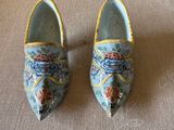 pair of blue and yellow shoes with floral designs on them sitting on a couch