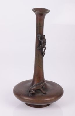un vase en bronze orné d'un oiseau sur fond blanc