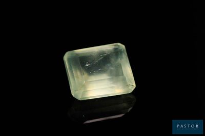 une pierre de quartz verte posée sur une surface noire, avec un fond noir