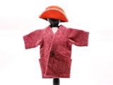 une petite poupée vêtue d'un manteau rouge et d'un bonnet rouge