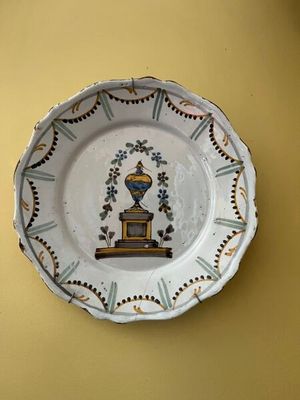 une assiette ornée d'une image représentant un vase, accrochée au mur