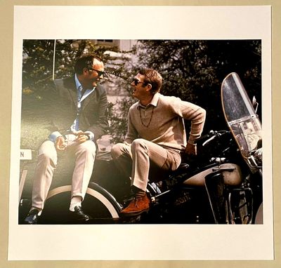 two men sitting on a motorcycle talking to each other