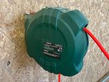 a green hose attached to a wall with a red cord