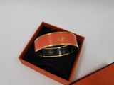 un bracelet orange et noir dans une boîte posée sur une surface blanche