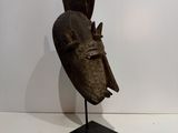 an old wooden mask on a stand in a white room