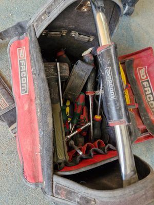 une sacoche à outils posée par terre, contenant des outils