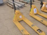 Trois chariots élévateurs jaunes sont garés dans un entrepôt, avec des palettes en arrière-plan.