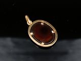 a close up of a gold pendant with a red stone