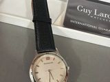 wrist watch with black leather strap and white dial on display in a box