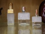 trois flacons de parfum posés sur une table à côté d'un flacon de parfum