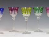 six different colored wine glasses are lined up in a row