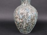 a blue and white vase sitting on a black surface