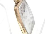 a gold watch with a white face on display in a glass case
