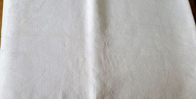 une serviette blanche posée sur une table en bois, à côté d'un couteau et d'une fourchette
