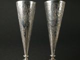 une paire de vases en argent posés sur une surface noire, sur fond noir