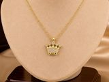 a gold necklace with a crown pendant on top of a mannequin