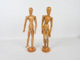 une paire de mannequins en bois placés l'un à côté de l'autre sur une surface blanche
