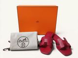 une boîte orange contenant une paire de sandales, à côté d'une paire de sandales rouges