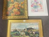 trois tableaux encadrés posés sur une table, avec un vase de fleurs et un autre vase de fleurs