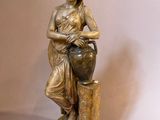 statue of a woman sitting on a tree stump holding a vase