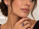 une femme portant un haut noir, des boucles d'oreilles violettes et une bague