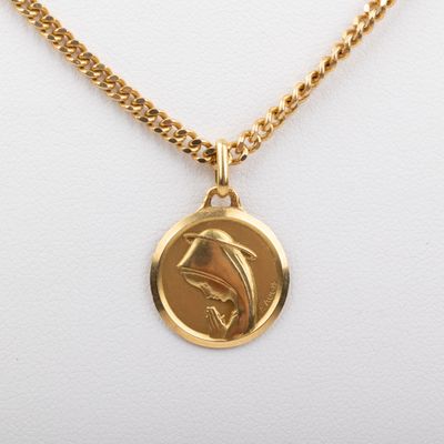 un gros plan d'un collier en or orné d'un dauphin