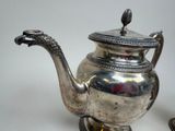 a silver teapot with a bird on top of it