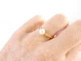 a woman ' s hand with a pearl ring on it